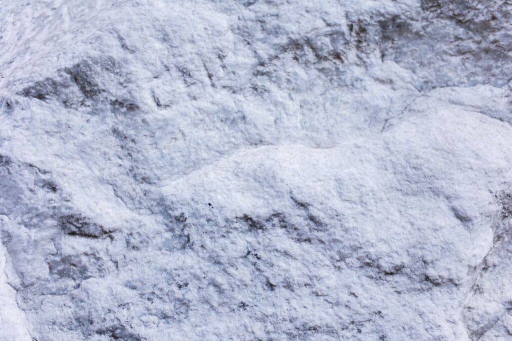 From above of abstract background of white cracked surface rocky stone with rough texture
